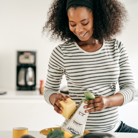 A happy woman grating cheese in the kitchen