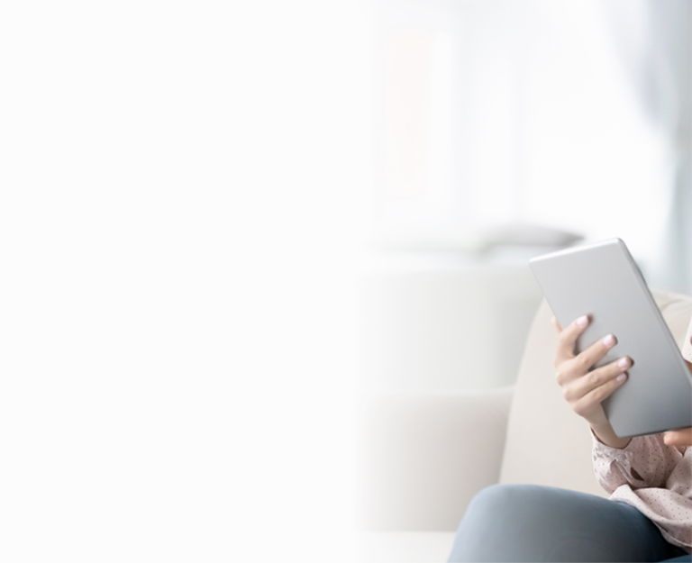 A woman sitting on the sofa, joyfully using a tablet