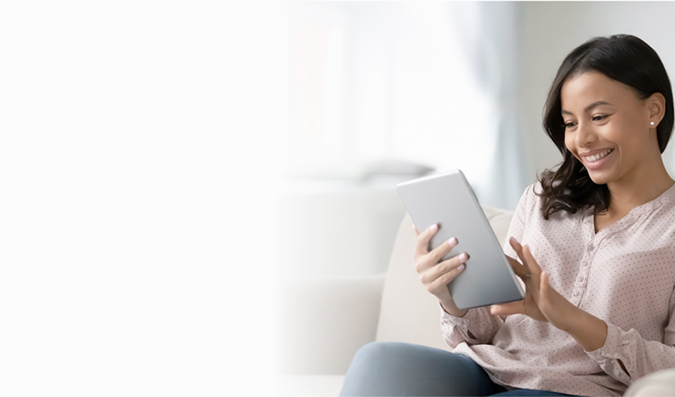 A woman sitting on the sofa, joyfully using a tablet