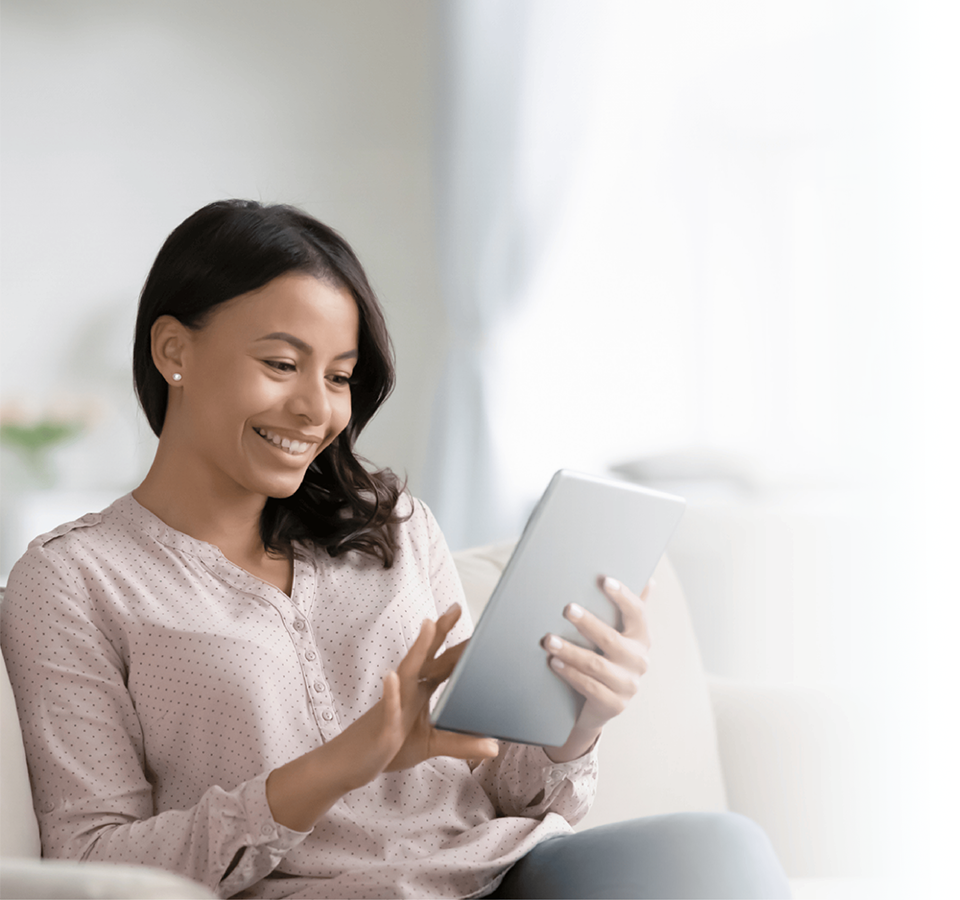 A smiling woman sitting on the sofa at home, using a tablet