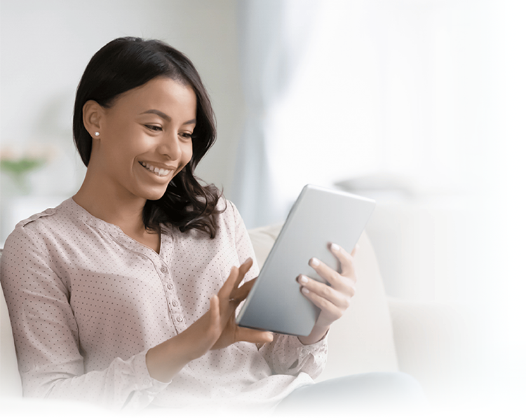 A smiling woman sitting on the sofa at home, using a tablet