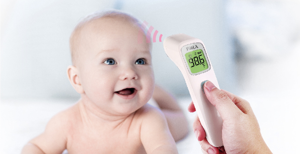 Holding a FORA IR42 thermometer to measure the baby's temperature