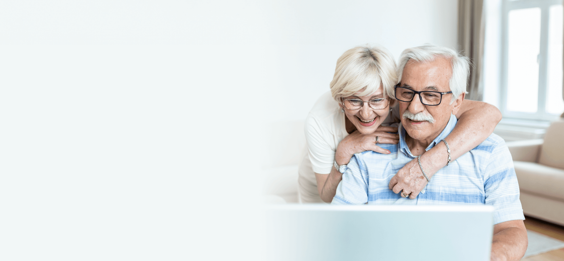 A smiling couple looking at a computer at home