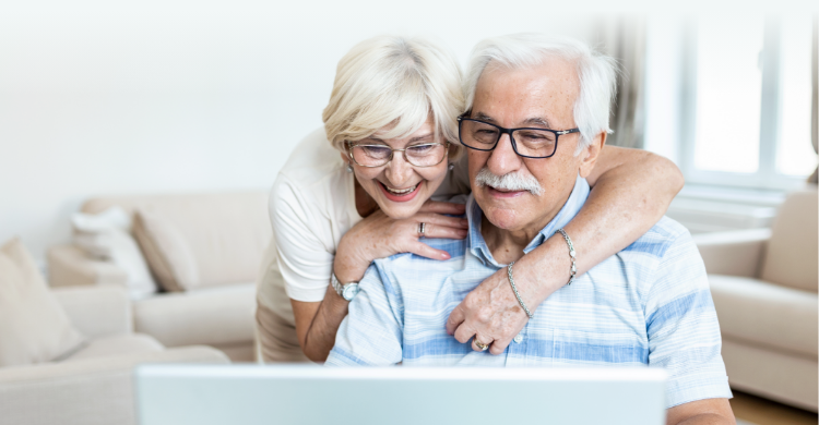 A smiling couple looking at a computer at home