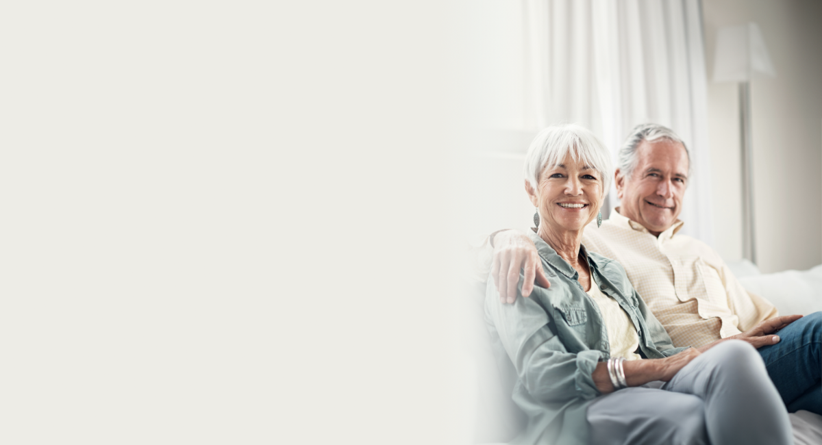 A happy man embracing his wife's shoulder, sitting on a sofa