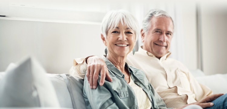 A happy man embracing his wife's shoulder, sitting on a sofa