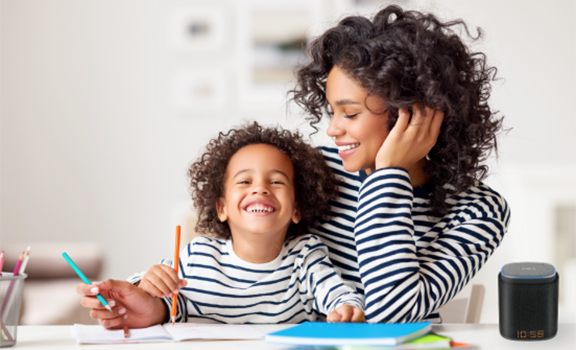 Mom accompanying her happy child drawing, with an iFORA IntelliSpeaker on the table