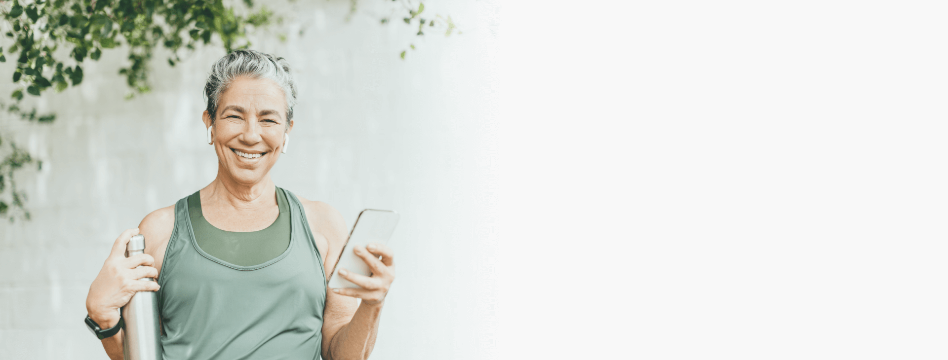 Healthy woman smiling, holding a water bottle and a smartphone