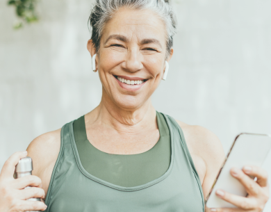 Healthy woman smiling, holding a water bottle and a smartphone