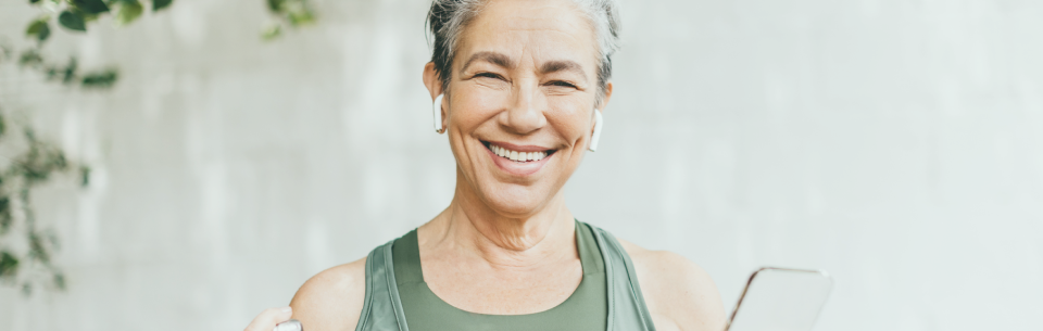 Healthy woman smiling, holding a water bottle and a smartphone