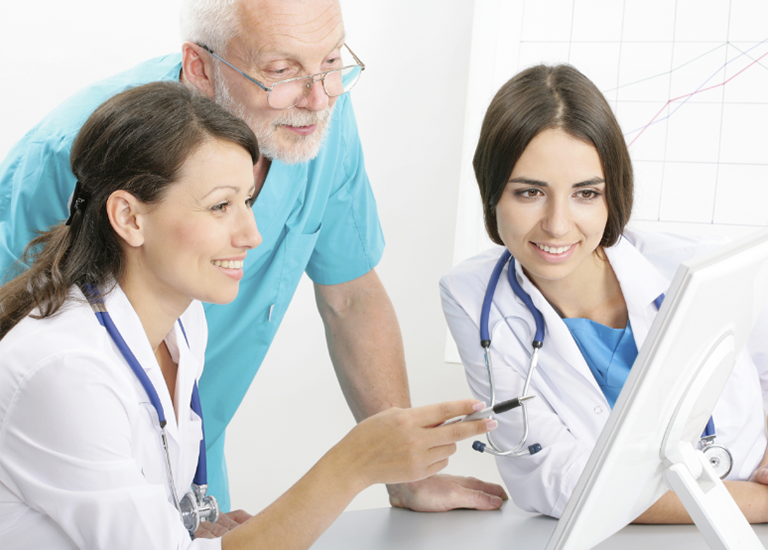 Physicians and patient looking at computer screen and discussing health