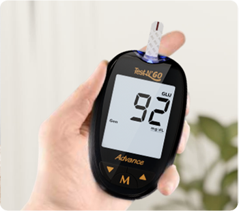 Holding a FORA Test N'GO Advance meter, with a strip inserted displaying blood glucose level