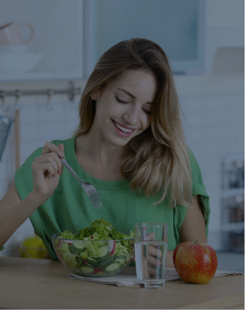 A woman sitting at a dining table eating salad