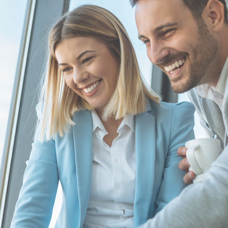 Two happy employees looking at a computer screen in the office