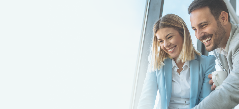 Two happy employees looking at a computer screen in the office