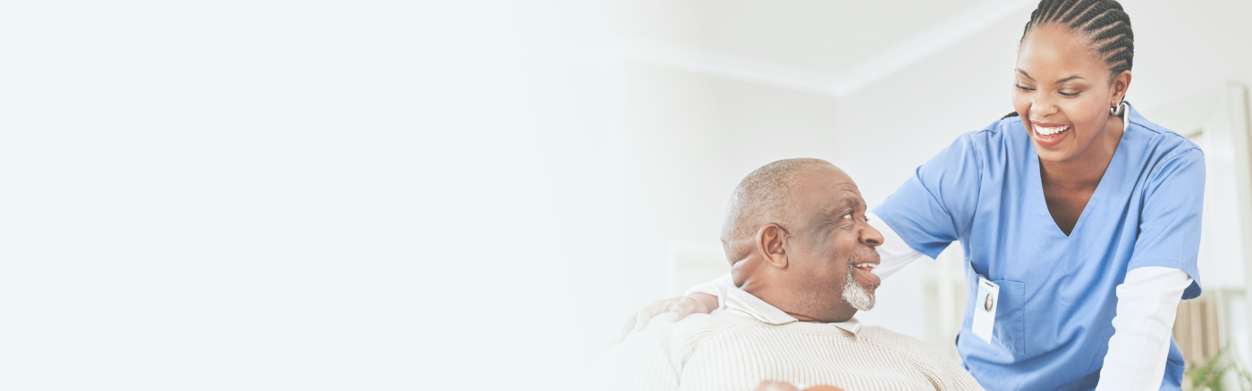 A smiling caregiver looking at elderly man, showing care and warmth