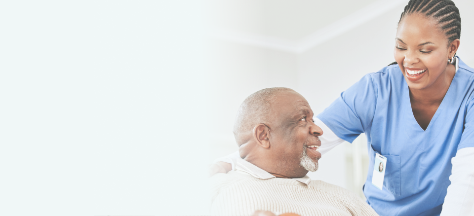 A smiling caregiver looking at elderly man, showing care and warmth