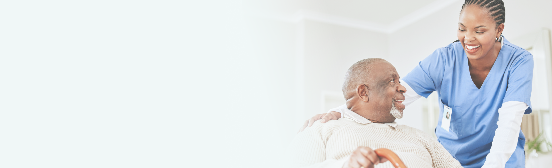 A smiling caregiver looking at elderly man, showing care and warmth