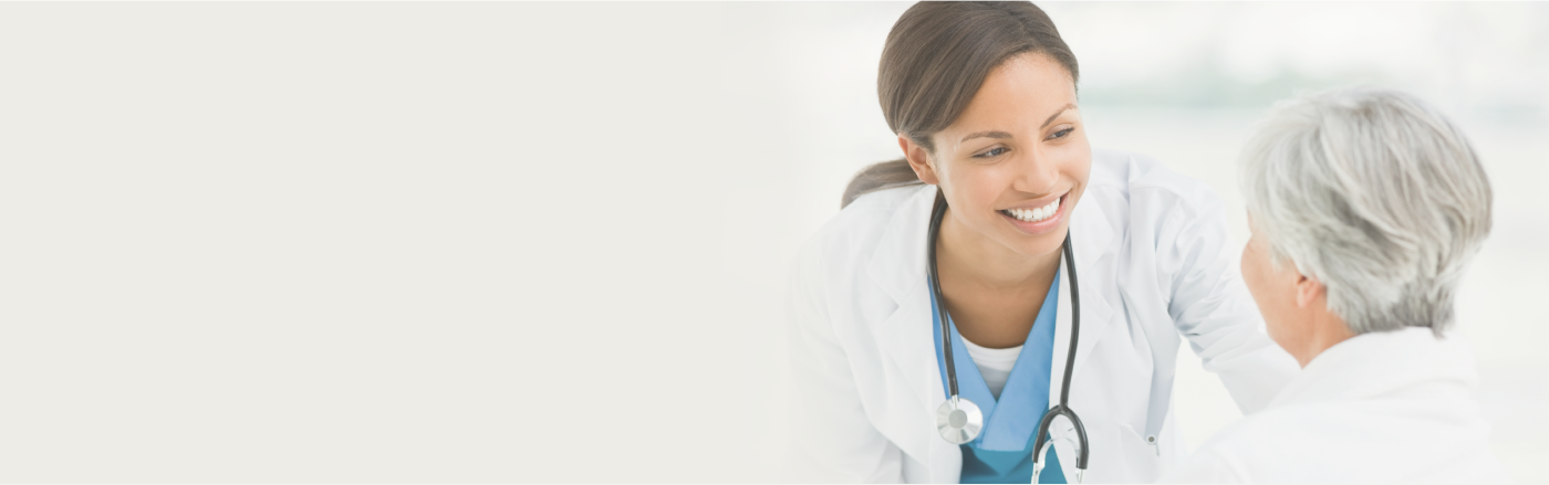 A smiling physician looking at an elderly woman, showing care and warmth