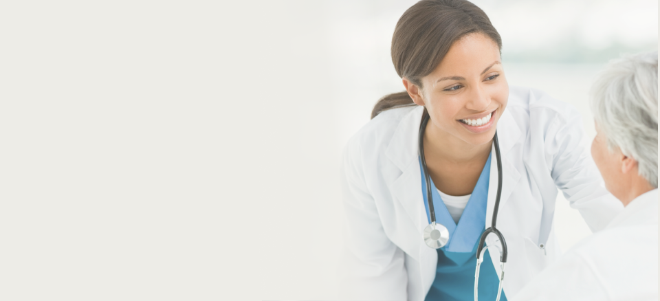 A smiling physician looking at an elderly woman, showing care and warmth