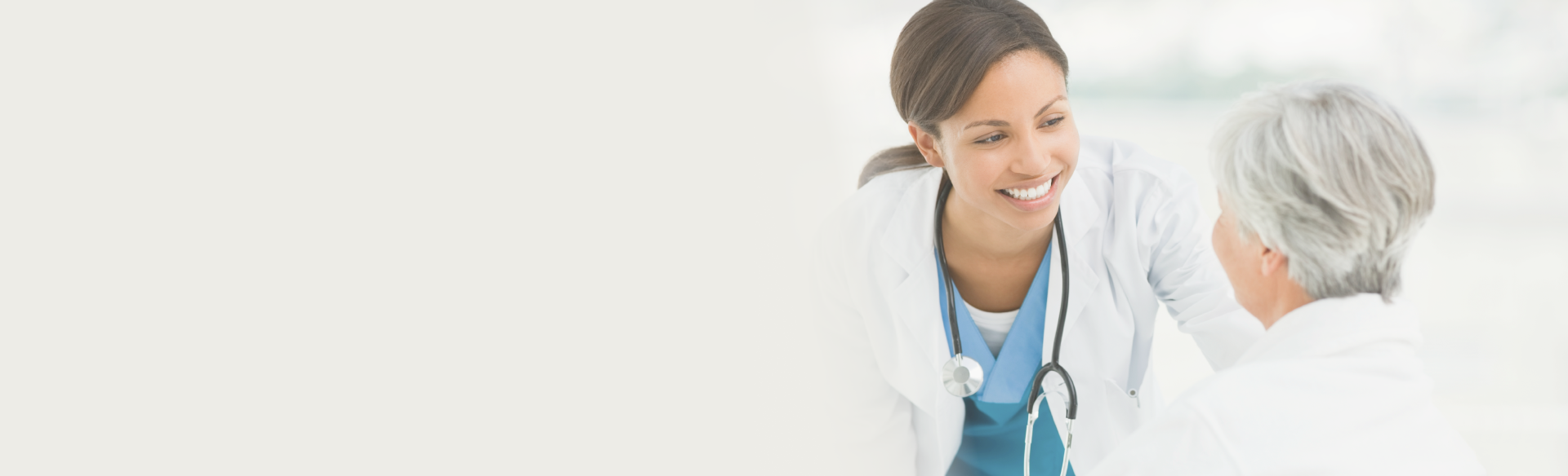 A smiling physician looking at an elderly woman, showing care and warmth