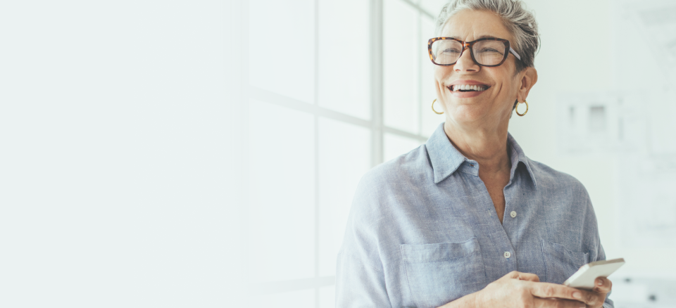 A happy woman holding a phone at home